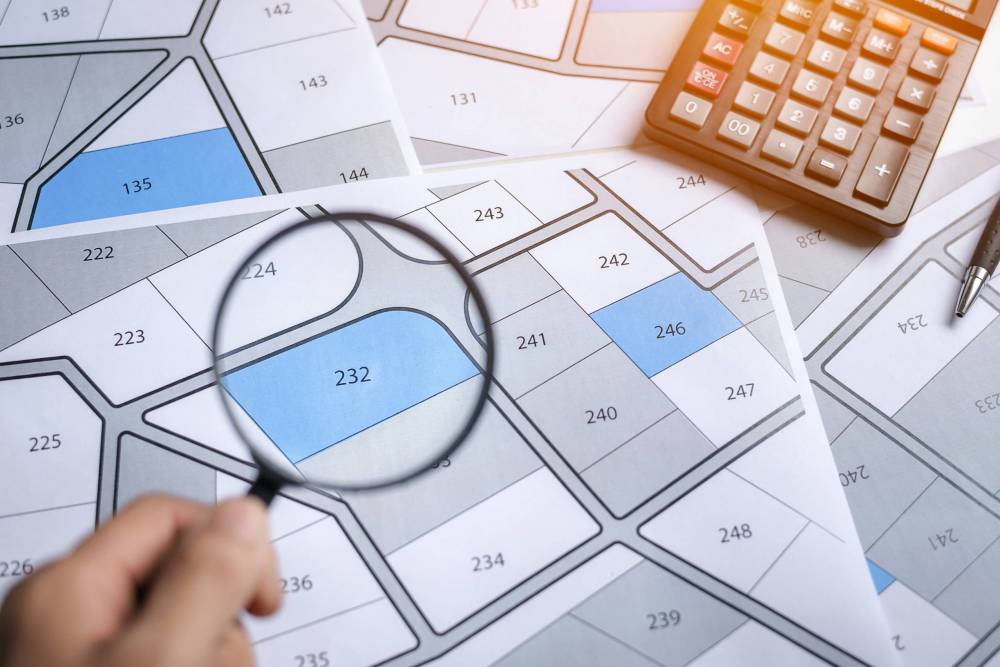 Hand,With,Magnifier,On,Cadastre,Map,Search,For,Assess,To